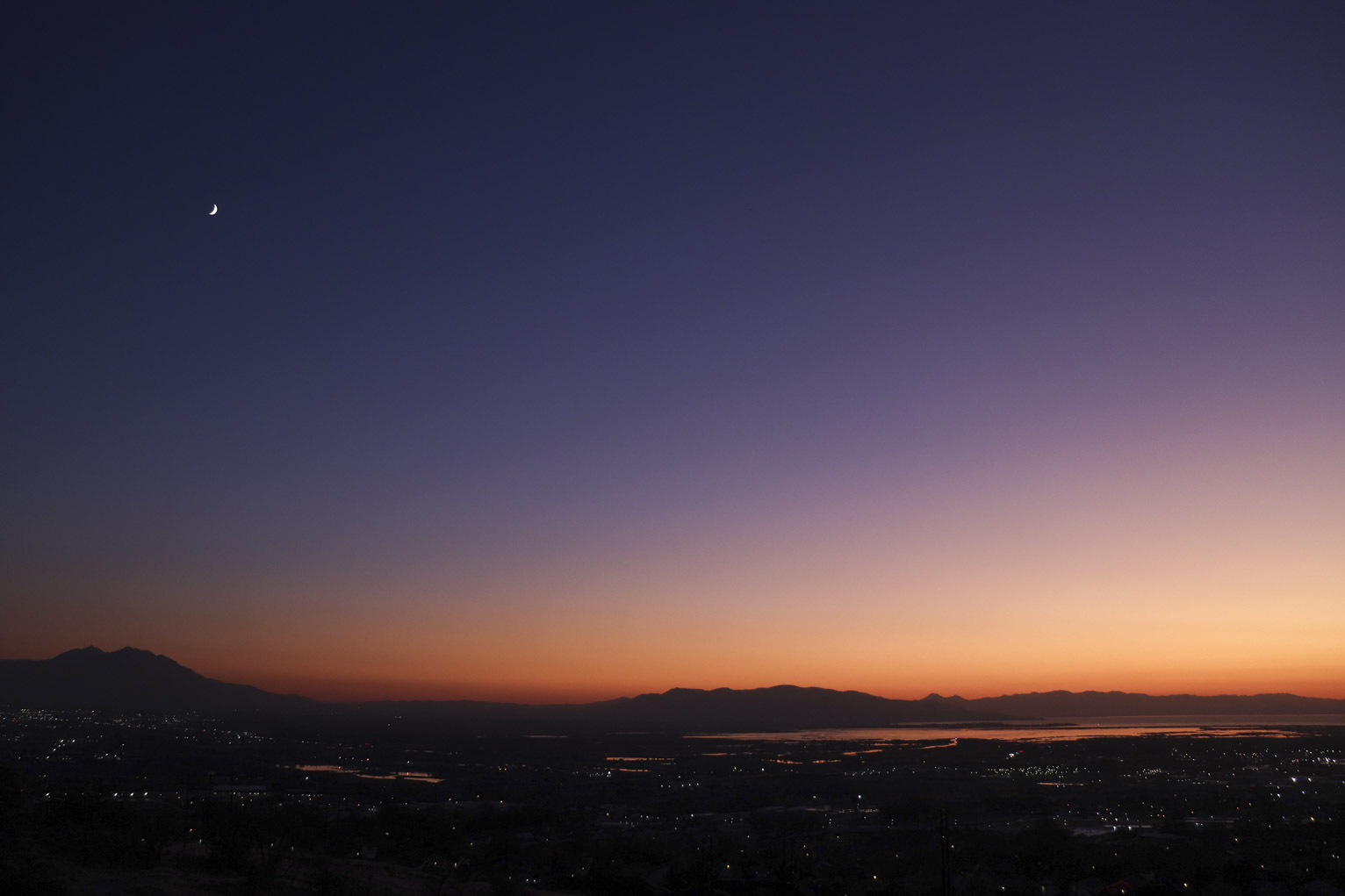 bright crescent moon over town lights just after sunset